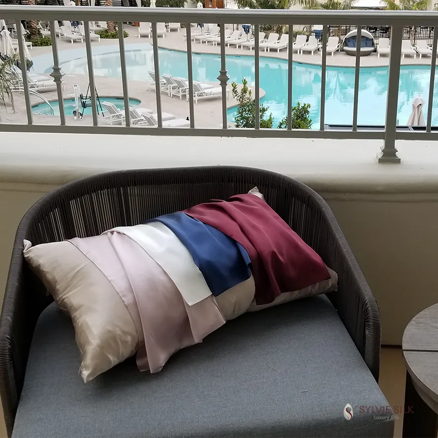 Sylvie Silk 22 momme envelope pillowcases silk charmeuse 20 colors displayed beside a resort pool