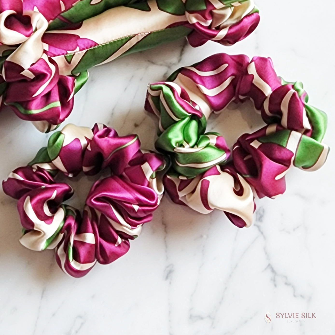 Close-up of two Monstera silk charmeuse scrunchies showing the gathered silk and botanical print